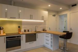 a kitchen with white cabinets and a wooden counter top at Cumberland Street deluxe apartment No5 in Dunedin