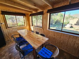 a wooden table and chairs in a room with windows at La Estancia del Molle in El Molle