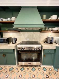 Una cocina con una estufa con campana verde. en MiraNamin Nest SAMPAGUITA Suite - Balconies, Garden View, Pet Friendly with a Fee, en Manila