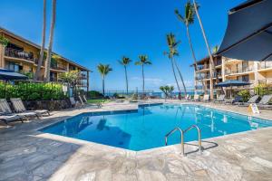 a swimming pool at a resort with palm trees at Ocean view with Loft in Kailua-Kona