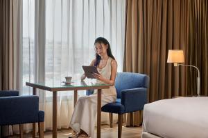 una donna seduta a un tavolo con un tablet di Dusit Princess Srinakarin Bangkok a Bangkok