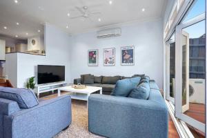 Una sala de estar con dos sofás azules y un televisor. en Bowen Street Family Retreat with Pool, en Melbourne