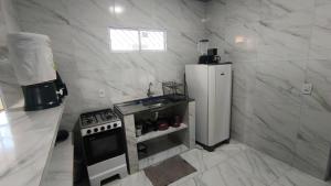 a white kitchen with a stove and a refrigerator at Casa de Maria Praia Suape in Cabo de Santo Agostinho