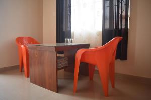 Dos sillas naranjas y una mesa de madera en una habitación. en Elysian Home Food & Stay, en Shillong