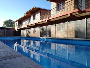 a swimming pool in front of a building at Los Olivos Apart in San Rafael