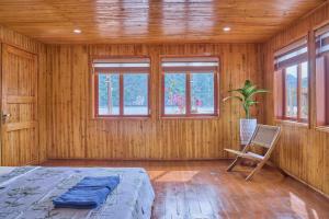 a bedroom with a bed and a chair and windows at Lan Ha Floating Homestay in Cat Ba +181 photos