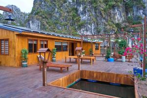 a building with a patio with benches and a pond at Lan Ha Floating Homestay in Cat Ba