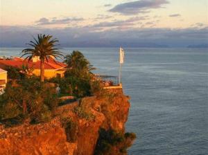a house on top of a cliff next to the ocean at Apartamento Raio de Sol in Caniço