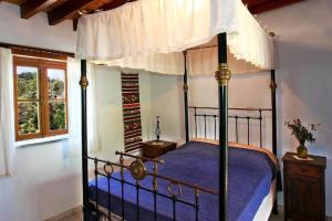 a bedroom with a canopy bed with a blue comforter at Narkissos Villa in Kallepia
