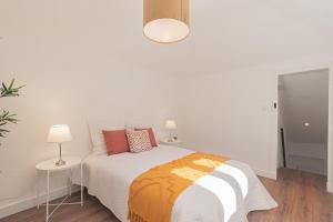 a white bedroom with a bed and two lamps at Stylish apartment in the heart of Lisbon in Lisbon