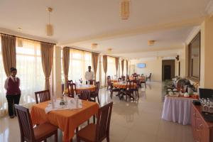 Ein Restaurant mit Tischen und Stühlen, im Hintergrund zwei Personen. in der Unterkunft Bete Daniel Hotel in Bahir Dar