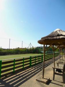 a tennis court with two benches and an umbrella at Mobile home in Sérignan