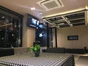 a dining room with a table and a tv on the wall at Melodi Hotel Dannok in Sadao