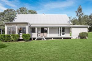 ein weißes Haus mit einem Rasen davor in der Unterkunft Madigan Cottages - Australiana in Lovedale