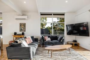 a living room with two couches and a table at Teringie Retreat with Breathtaking Views in Norton Summit