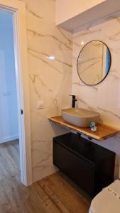 Un baño con un lavabo y un espejo sobre un mostrador. en Apartamentos Playa de Camariñas, en Camariñas