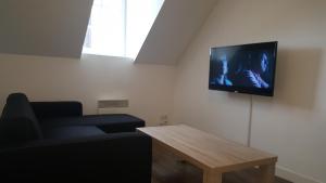 a living room with a couch and a tv on the wall at Au Pigeon Blanc in Andouillé