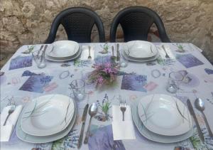 a table with plates and utensils on a table at Ema in Prvić Šepurine