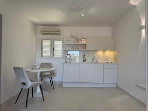 a kitchen with white cabinets and a table and chairs at Oleander Apartment & Room Centar in Hvar