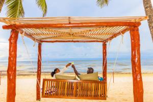 2 personnes assises sur une balançoire sur la plage dans l'établissement PrideInn Flamingo Beach Resort & Spa Mombasa, à Mombasa