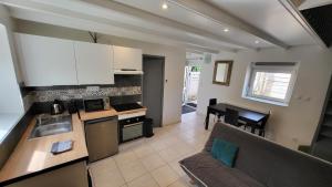 a kitchen and a living room with a couch at KerElo Le Ptit St Roch, maisonnette cosy, mer 5km, Ploudalmezeau in Ploudalmézeau +9 photos