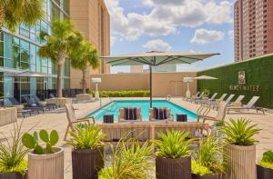 a pool with chairs and an umbrella in a courtyard at Hyatt Regency Houston Galleria in Houston