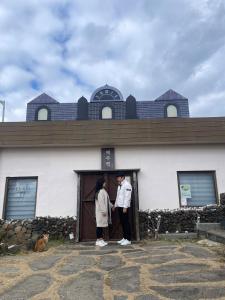 two people standing in the doorway of a building at Jeju Station in Jeju