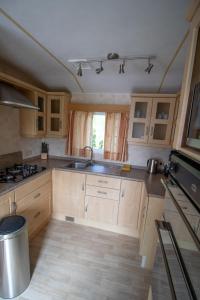 a kitchen with wooden cabinets and a sink at Hof Nieuwerkerk Chalet 2 in Arnemuiden