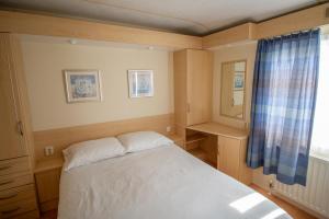 a small bedroom with a bed and a window at Hof Nieuwerkerk Chalet 2 in Arnemuiden
