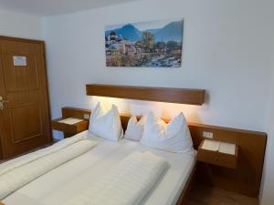 una camera da letto con un letto con lenzuola e cuscini bianchi di Active B&B Prairerhof a Scena