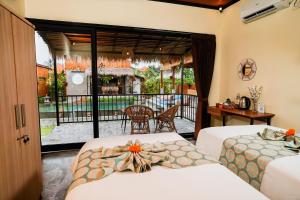 two beds in a room with a view of a balcony at Nila Chandra Bungalows in Ubud +45 photos