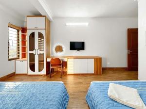 a bedroom with two beds and a desk and a television at Minh Đức Hotel Quan Lạn - Thứ 7 chỉ nhận 3 phòng trở lên in Quan Lạn