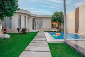 une cour avec une piscine et de l'herbe verte dans l'établissement شاليهات ومنتجعات ارجان بارك, à Riyad