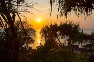 um pôr do sol na praia com palmeiras em Lanta Coral Beach Resort em Ko Lanta