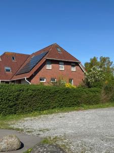 a red brick house with a black roof at FeWo-Julius am Weser-Sandstrand in Berne