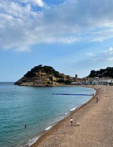 a beach with people on the sand and the water at Hotel Don Juan Tossa in Tossa de Mar