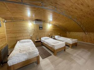 two beds in a room with a wooden wall at Guest house Amirhan in Bokonbayevo