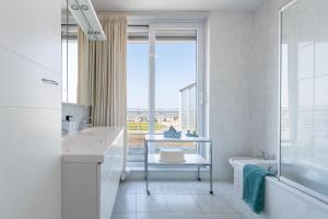 a bathroom with a sink and a tub and a window at Penthouse Ostend with Seaview in Ostend +6 photos