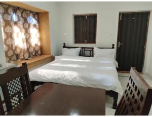 斋沙默尔Hotel Namaste jaiselmer inn, Jaiselmer的一间卧室，配有两张床、一张桌子和窗户