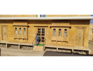 斋沙默尔Hotel Namaste jaiselmer inn, Jaiselmer的一名男子正在清洁一座木质建筑的正面