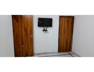 斋沙默尔Hotel Namaste jaiselmer inn, Jaiselmer的一间设有两个木门的房间和墙上的电视