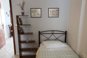 a small bedroom with a bed and two shelves at Eleni's Summer Apartment in Tolo