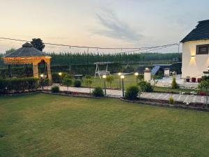 a backyard with a gazebo and a lawn with lights at Dhawanfarms in Bela