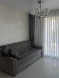 a couch in a living room with a window at Bright Gray Нові затишні апартаменти біля центру in Ternopilʼ