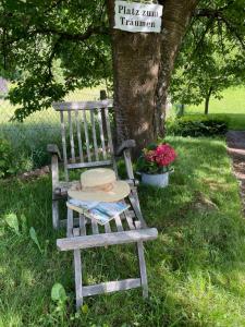a wooden chair sitting in the grass next to a tree at Am Kesperbaum in Germerode