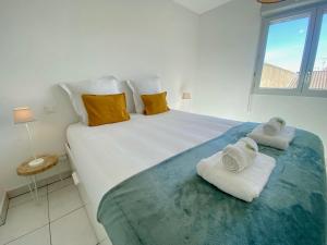 a bedroom with a large bed with towels on it at ''Loulou'' T1 moderne et lumineux, centre ville, wifi, parking in Sète