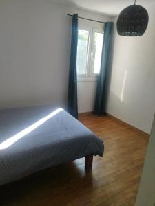 a bedroom with a bed with blue curtains and a window at L'étang du griffolet in Ussac