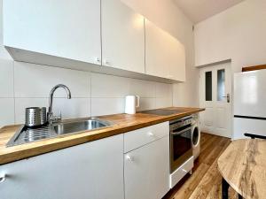 a kitchen with white cabinets and a sink and a table at Pokoje na Monte Cassino 26 in Sopot +15 photos