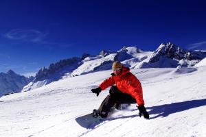 Un uomo che cavalca uno snowboard giù per una montagna innevata di Hotel Park a Fiesch