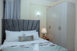 a bedroom with a large bed with a gray headboard at The Nordic Nest in Ruiru
